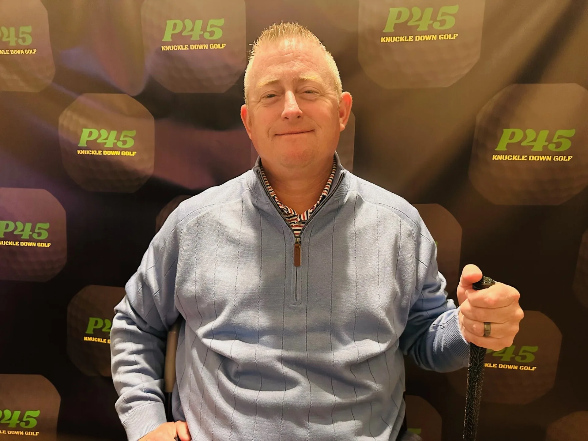 Ryan Carpenter holding a golf club in front of a P45 branded backdrop